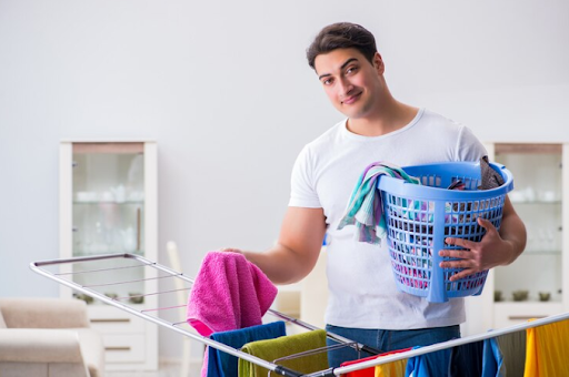 A man holding a basket of laundry filled with vibrant clothes, showcasing the quality of Dry Cleaning Services Addington's professional care.
